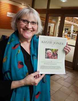 Kizzie Jones with Skagit Valley Writers League speech flyer at Burlington Library.